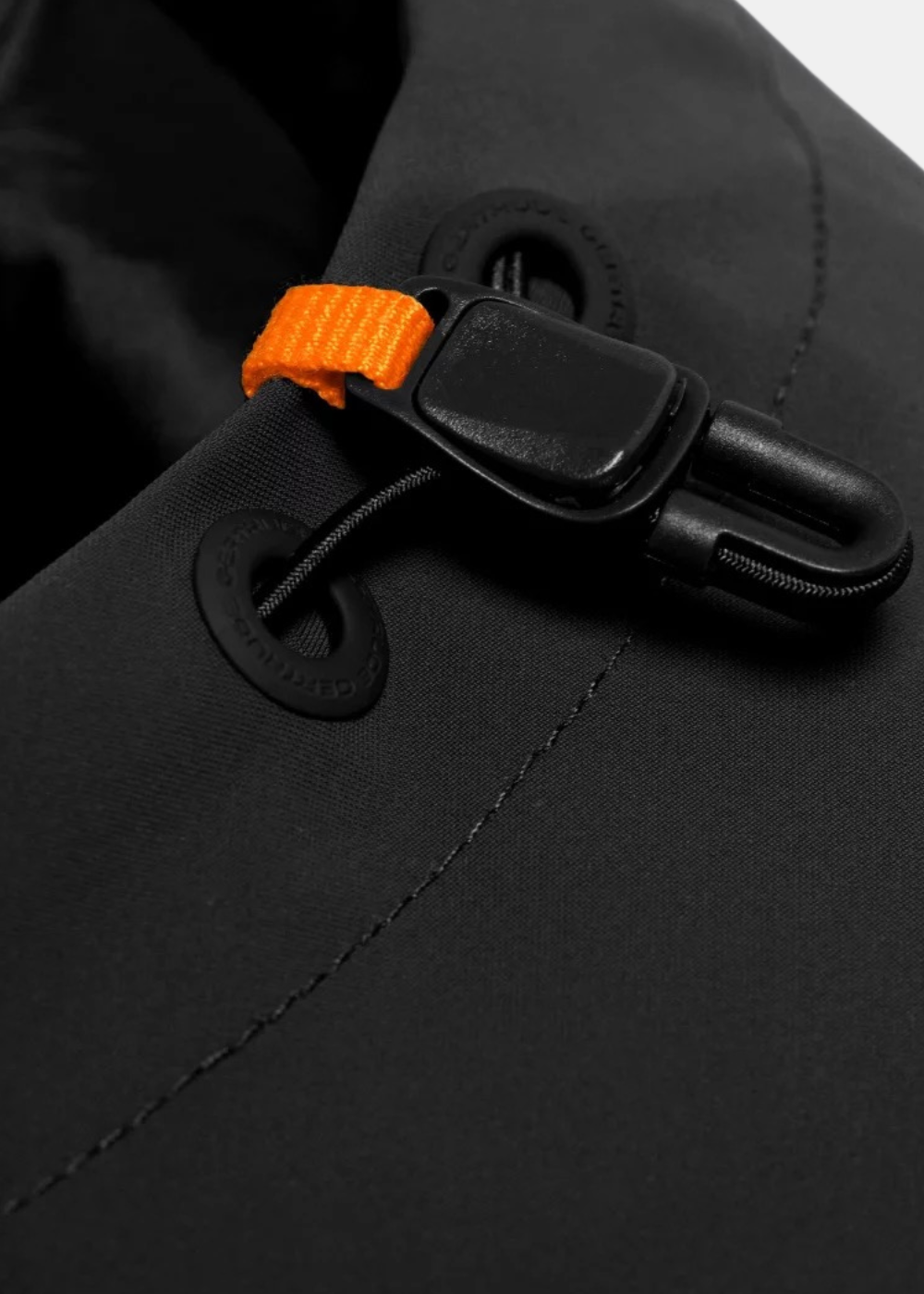 Gros plan sur le stoppeur de cordon d'ajustement noir et orange de la capuche de la veste Gertrude