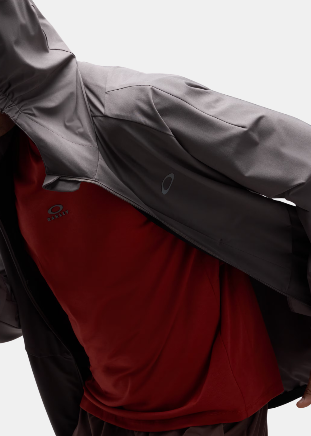 Gros plan en mouvement du mannequin portant la veste Oakley Edge Force ouverte sur un t-shirt rouge