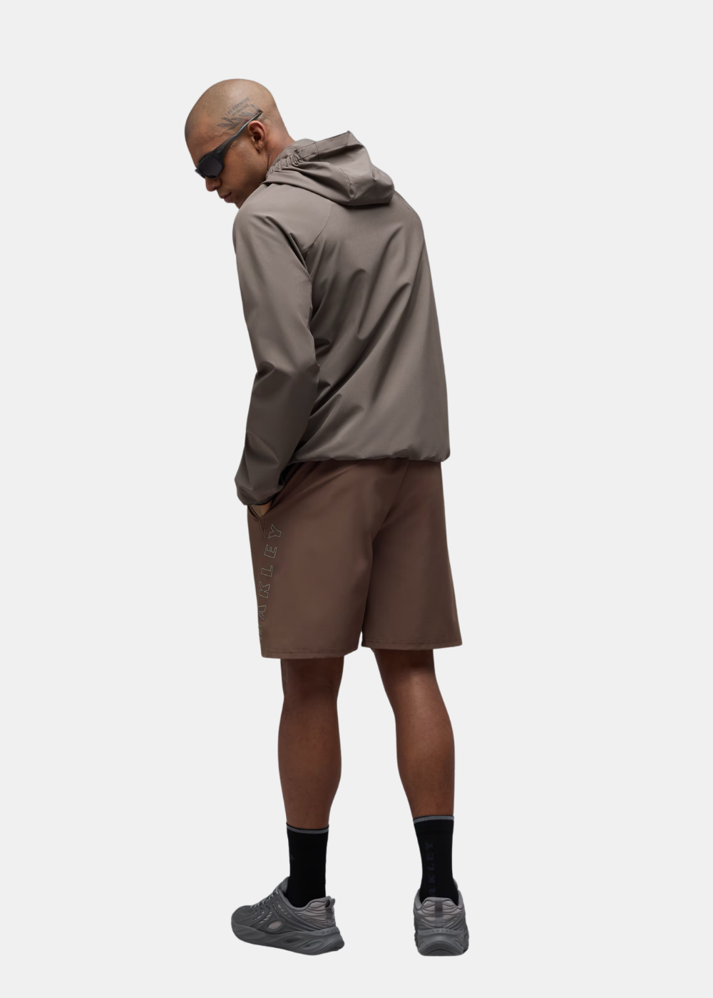 Vue de trois-quarts dos du mannequin portant la veste Oakley Edge Force taupe et short marron
