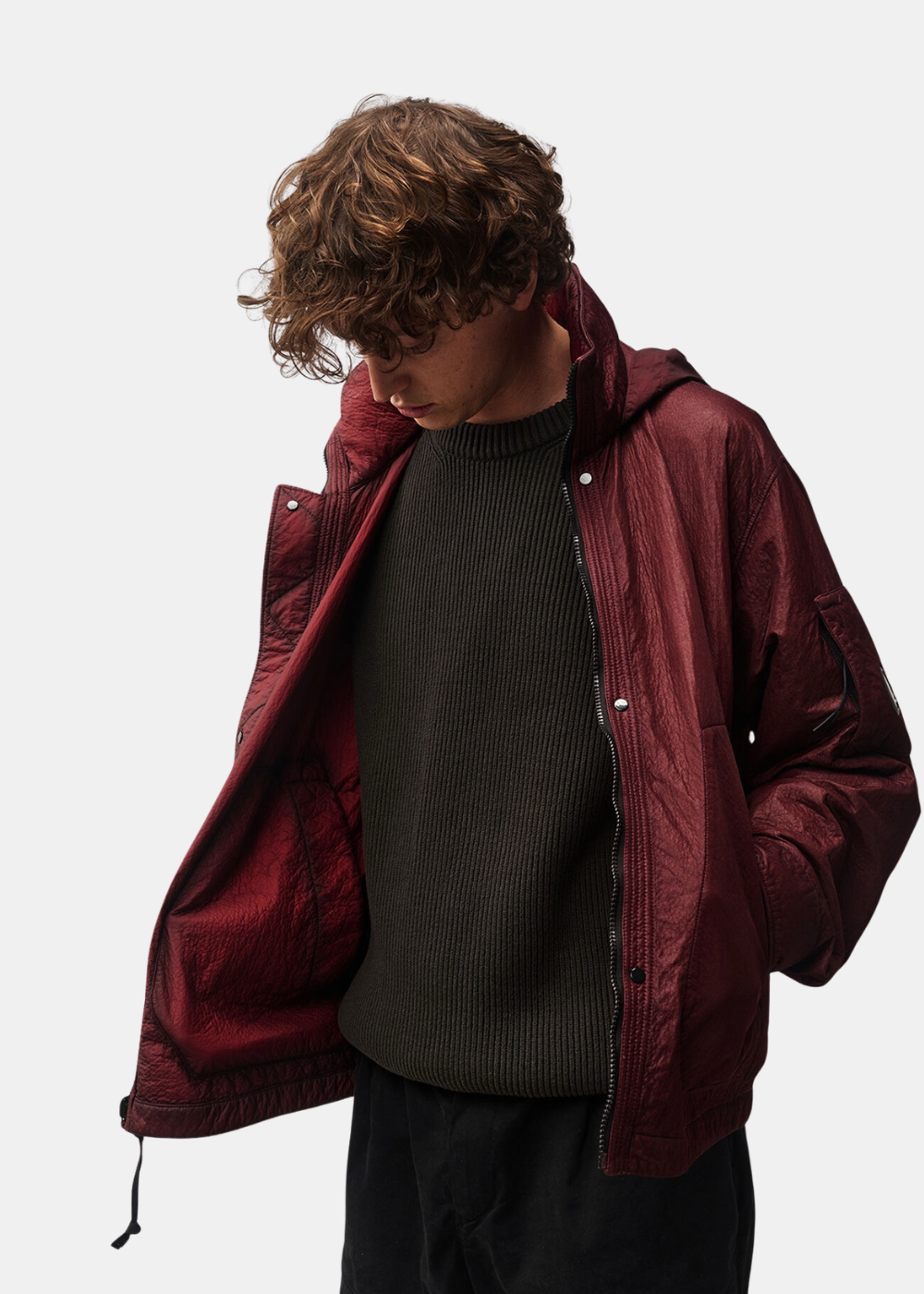 Gros plan sur le mannequin ouvrant la veste réversible bordeaux C.P. Company pour montrer l'intérieur et la doublure