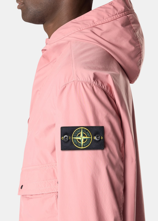 Gros plan sur le badge boussole emblématique Stone Island sur la manche d'une veste rose.