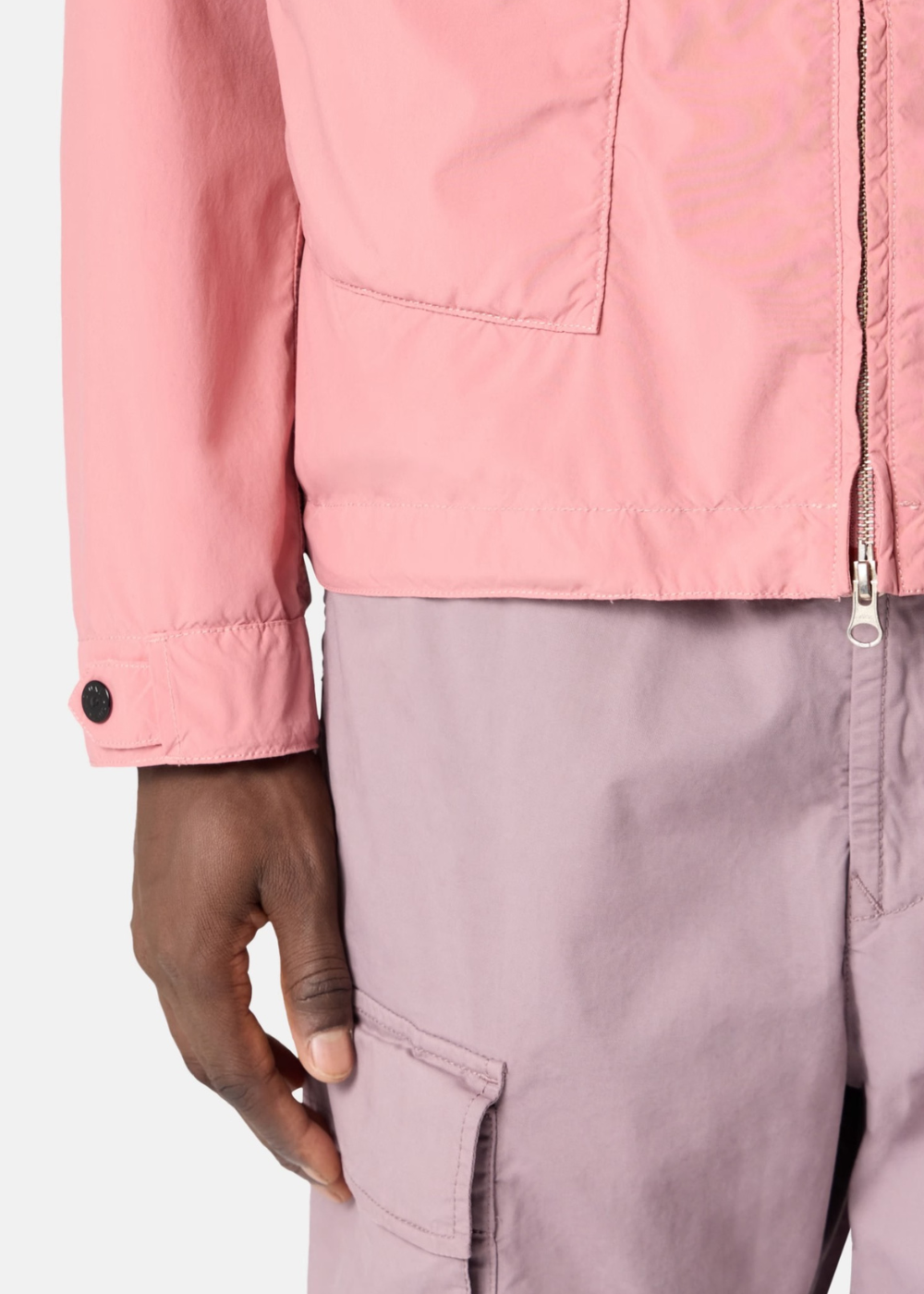 Vue rapprochée de la taille d'une veste rose Stone Island portée avec un pantalon lilas.