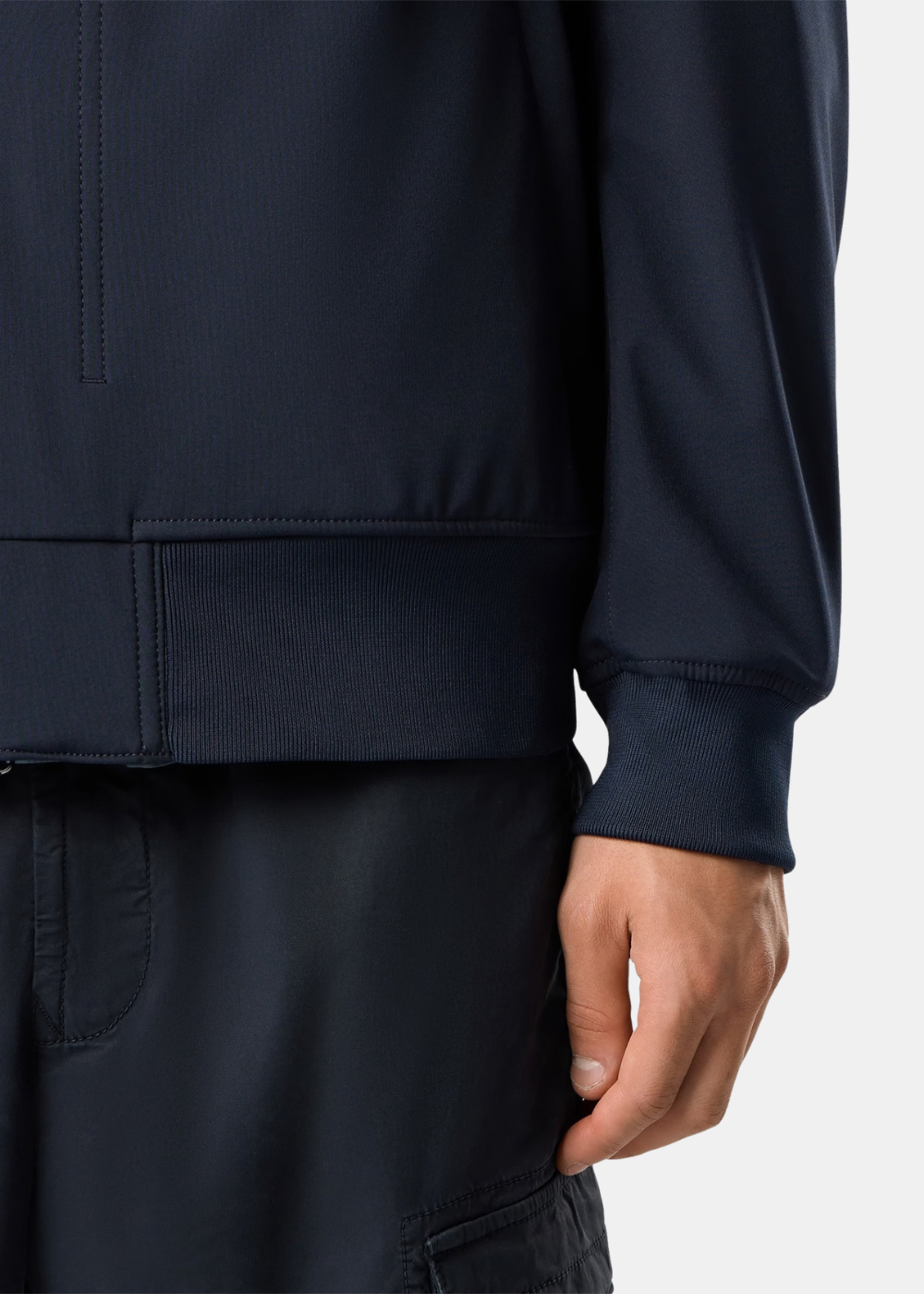 Primer plano del dobladillo acanalado y puño elástico de la chaqueta ligera Stone Island azul marino