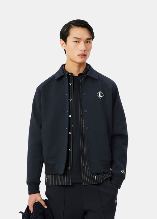 Veste teddy marine portée par un mannequin, soulignant le badge poitrine et les bords-côtes rayés.