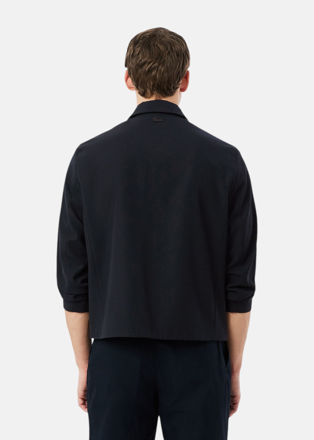 cette photo montre un mannequin de dos portant la Veste homme en twill lacoste bleu marine. Cette photo révèle la coupe boxy de cette veste legere en laine.