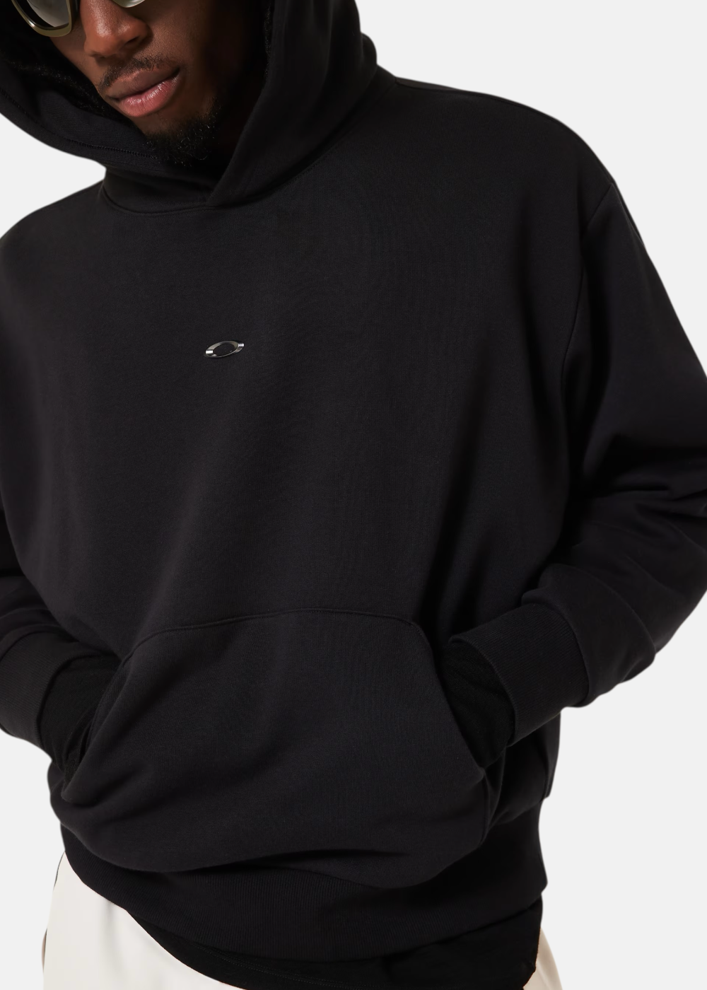 Gros plan sur le logo Oakley iconique au fini métallisé contrastant sur le molleton noir.