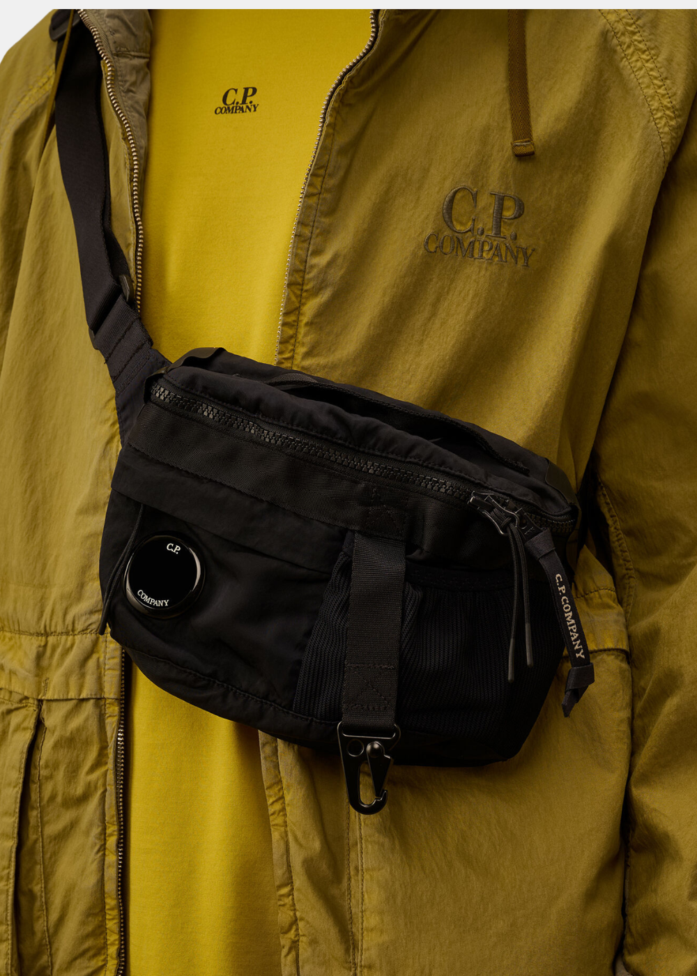 zoom sur la sacoche banane cp company en nylon noir portée en bandouliere par un mannequin